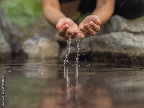 Tablou pe pânză Close-up image of hands cupping water from a stream in a forest