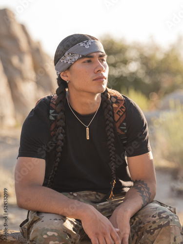 Vertical portrait of a young Indigenous man in the outdoors 