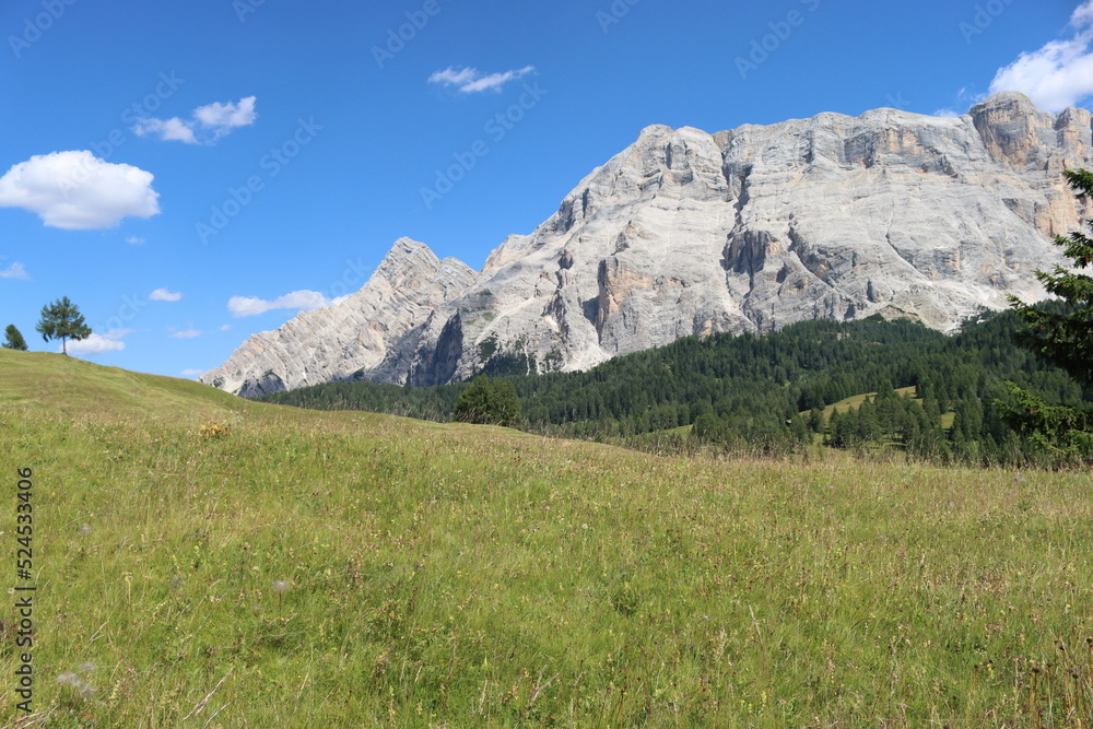 Val Badia, Italy-July 17, 2022: The italian Dolomites behind the small village of Corvara in summer days with beaitiful blue sky in the background. Green nature in the middle of the rocks.