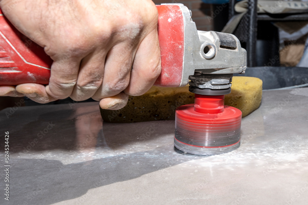 Naklejka premium The tiler drills porcelain stoneware with a diamond crown. Close-up, selective focus.