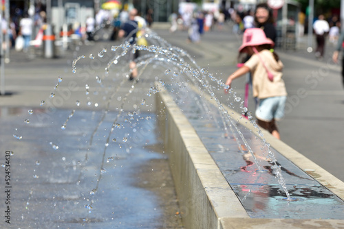 Ein Mädchen kühlt sich an einem Wasserspiel in Wien (Bezirk Favoriten) ab