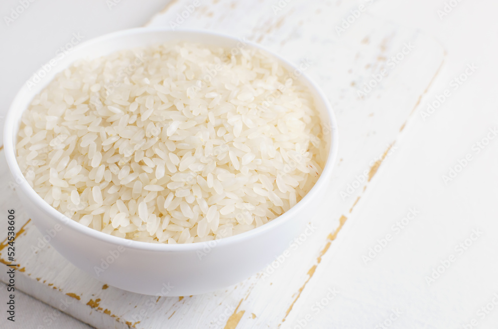 Dry camollino rice in a white ceramic bowl on an old kitchen board. The concept of healthy eating. Copy space. Selective focus. Horizontal orientation.