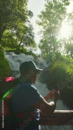 man is pouring coffee with neaar waterfall with the autumn scenery in the background photo