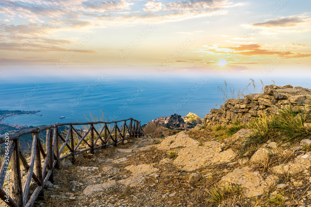 Fototapeta premium mountain landscape with a hiking trail leading to a mountain town and beautiful blue seashore far away