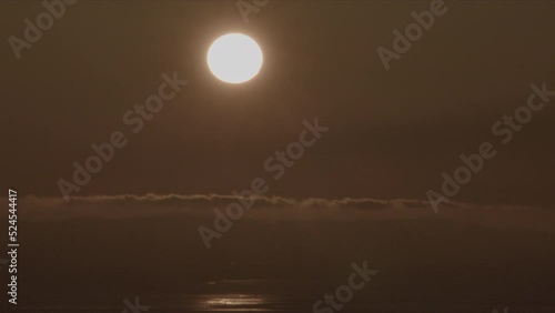 Sun in Sky with Distant Hills and Lake