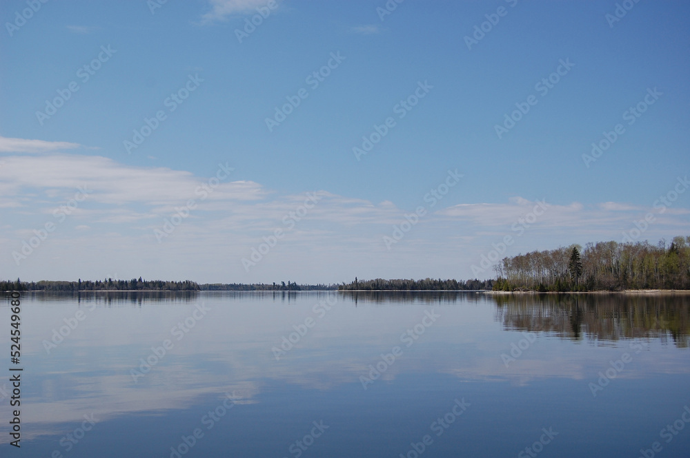 Breathtaking view of the natural reflections cast upon the calm glossy waters of Lac Seul, Ontario, Canada.