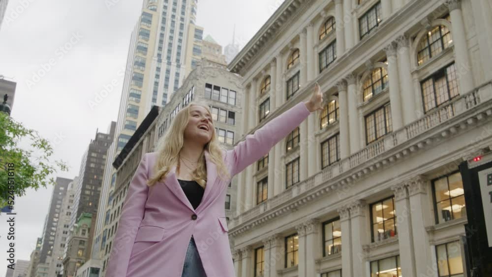 Young girl catching taxi in urban city centre. Business woman smiling and happy outside in New York. Manhattan cityscape and skyscraper background. Successful lady in NYC, big city life Young girl catching taxi in urban city centre. Business woman smiling and happy outside in New York. Manhattan cityscape and skyscraper background. Successful lady in NYC, big city life