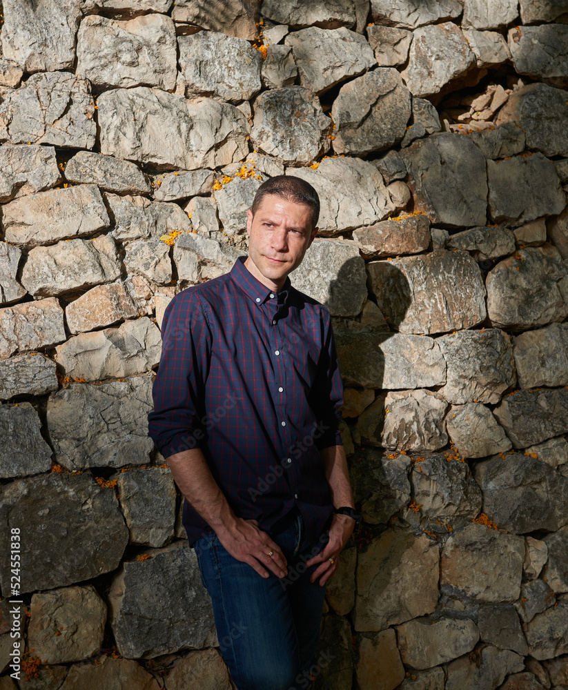 young man in blue shirt posing behind a wall young man in blue shirt posing behind a wall