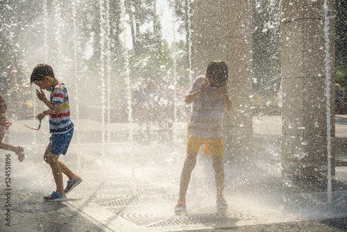 Fototapeta Naklejka Na Ścianę i Meble -  Boy having fun in water fountains. Child playing with a city fountain on hot summer day. Happy kids having fun in fountain. Summer weather. Active leisure, lifestyle and vacation