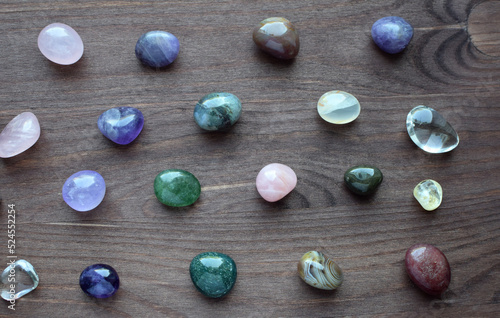 Semi-precious stones of different colors. Amethyst, rose quartz, agate, apatite, aventurine, olivine, turquoise, aquamarine, rock crystal on a wooden background.