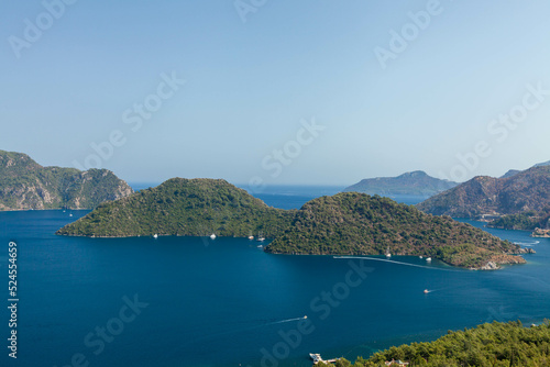 Marmaris, Turkey – Beautiful view of the islands and the crystal clear water of the bay at sunny day with its misty green mountains at background and the blue bay.