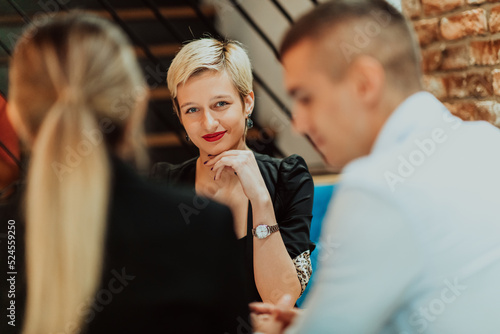 Happy businesspeople smiling cheerfully during a meeting in a coffee shop. Group of successful business professionals working as a team in a multicultural workplace.
