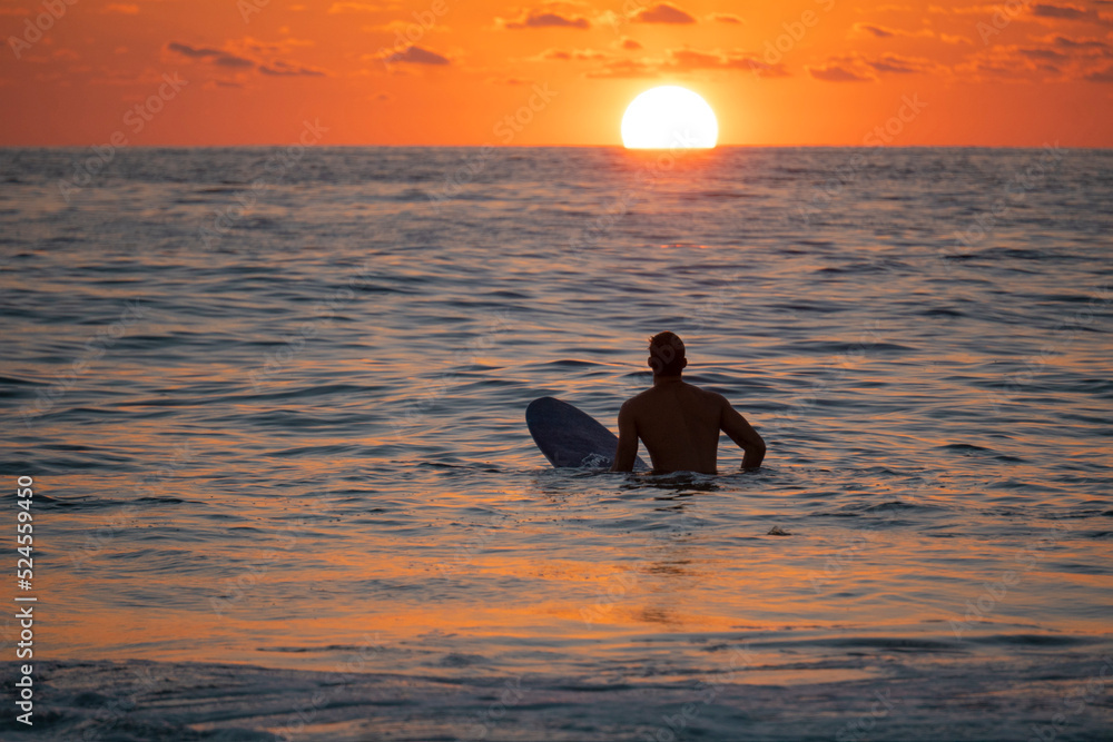 Silhouette of Surfer waiting on the line up for a wave at sunrise or sunset
