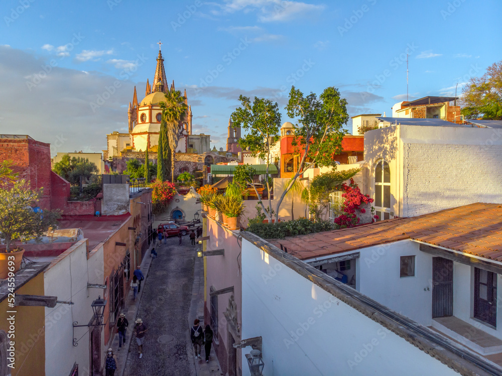 Fototapeta premium Aerial Drone Shot From Narrow street in San Miguel de Allende Cathedral at evening light in Guanajuato, Mexico