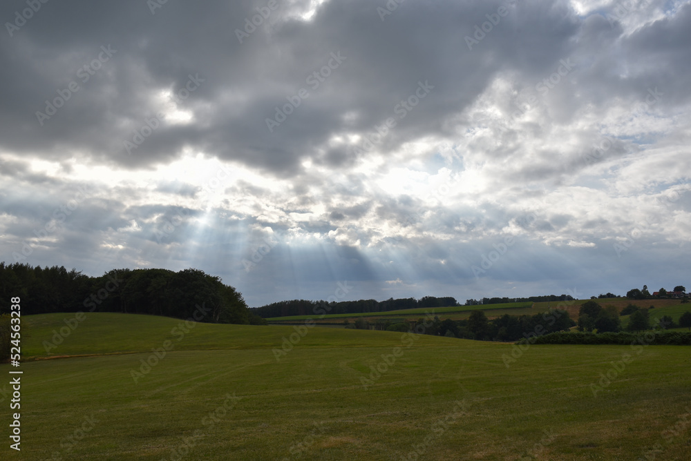 cloudy sky with sunbeams breaking through a field in germany cloudy sky with sunbeams breaking through a field in germany