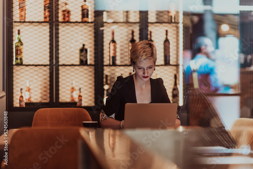 Businesswoman sitting in a cafe while focused on working on a laptop and participating in an online meetings. Selective focus. High quality photo