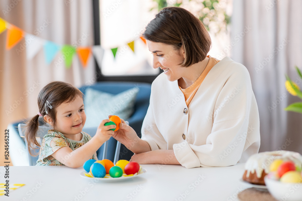 holidays, family and people concept - happy little baby daughter and mother tapping colored easter eggs at home holidays, family and people concept - happy little baby daughter and mother tapping colored easter eggs at home