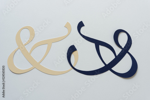 two duelling paper ampersands on blank paper