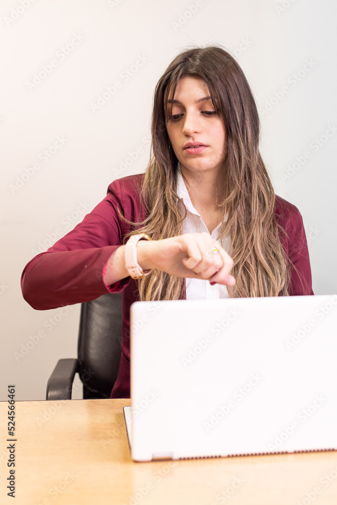 Beautiful woman working on her laptop while watching the time. Beautiful woman working on her laptop while watching the time.