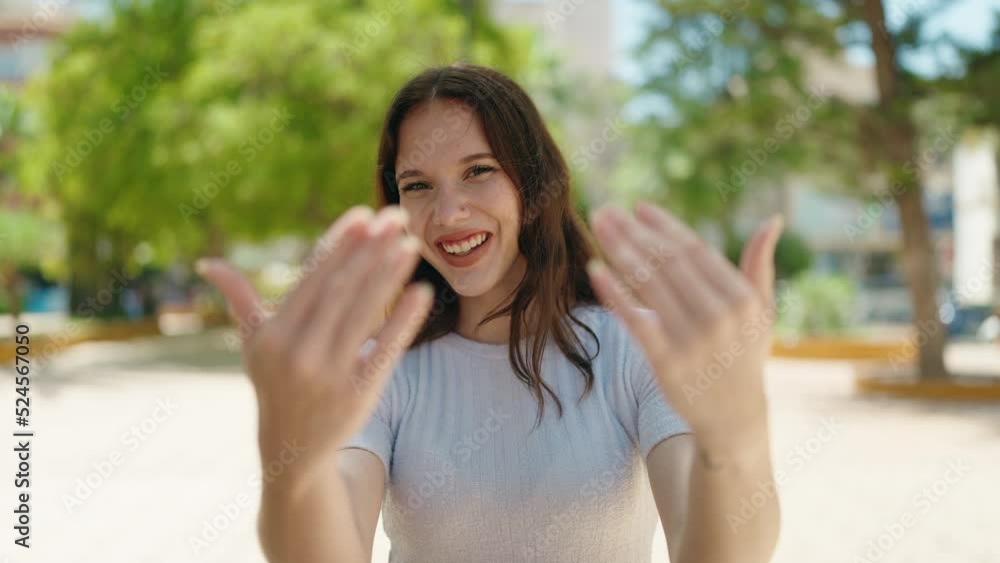 Young woman smiling confident doing coming gesture with hands at park Young woman smiling confident doing coming gesture with hands at park