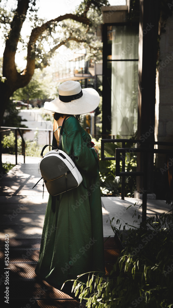 pregnant woman wearing a green dress, a backpack and a hat