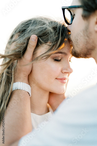Man kisses woman on the forehead  holding her head in his hands. Portrait