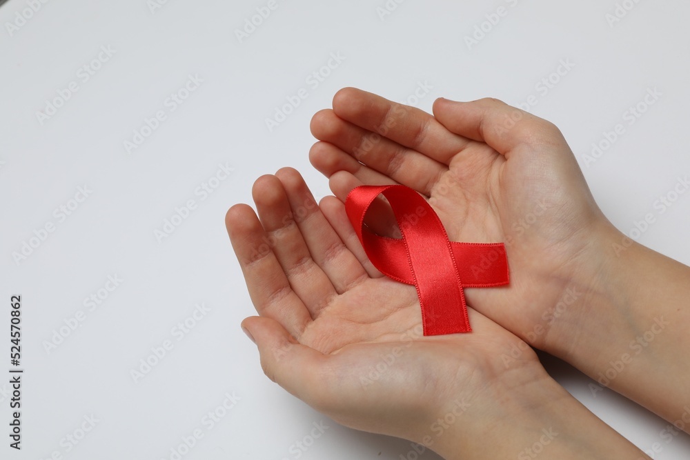 Little girl holding red ribbon on white background, closeup. AIDS disease awareness Little girl holding red ribbon on white background, closeup. AIDS disease awareness