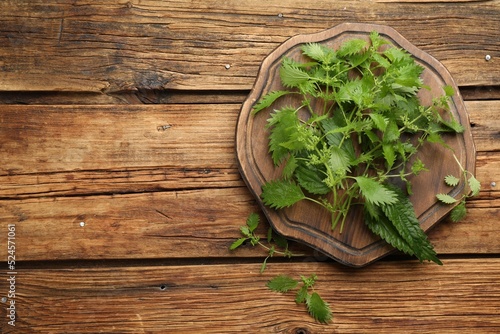 Fresh stinging nettle leaves on wooden table, flat lay. Space for text