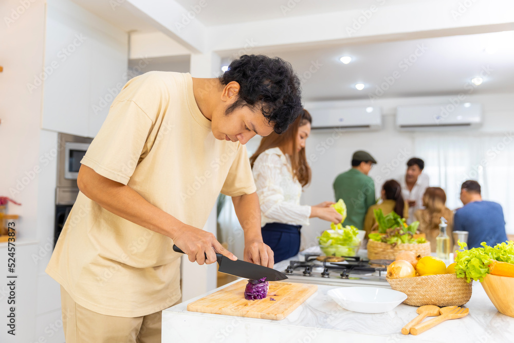 Asian man using knife cutting fresh red cabbage on cutting board in the kitchen at home. Happy female enjoy cooking and having dinner eating healthy food on holiday vacation Asian man using knife cutting fresh red cabbage on cutting board in the kitchen at home. Happy female enjoy cooking and having dinner eating healthy food on holiday vacation