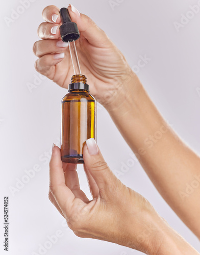 Skincare serum, essential oil and cosmetic product in woman hand for perfect, smooth skin or reduce wrinkles isolated on studio background. Closeup hands using body care or anti aging liquid drop photo