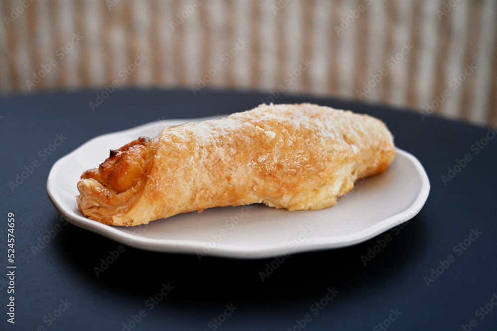 Close up of a quesito (cream cheese-filled pastry twist from Latin America) on a plate | Un quesito (hojaldre latinoamericano relleno de queso crema) en un plato Close up of a quesito (cream cheese-filled pastry twist from Latin America) on a plate | Un quesito (hojaldre latinoamericano relleno de queso crema) en un plato