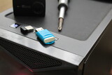 A USB memory stick, screwdriver and an action camera on a computer case. Black concept