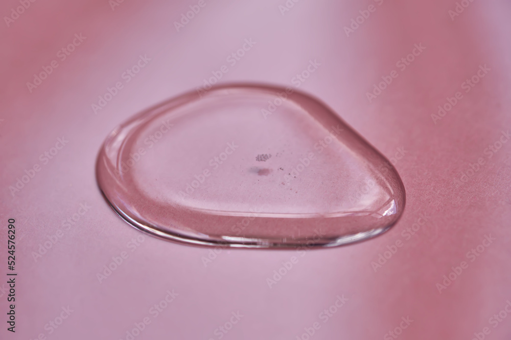 A drop of cosmetics or perfume on a pink background. A drop of cosmetics or perfume on a pink background.