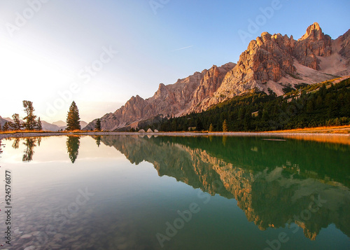 Dolomites Group Cristallo - Little pond in Val Padeon near Cortina d Ampezzo. Calm mountain lake reflecting rugged peaks and trees under a vibrant sunrise sky in a serene landscape photo