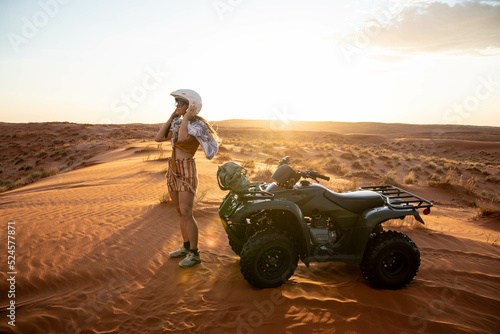female traveler putting on helmet before riding quad bike through desert of namibia