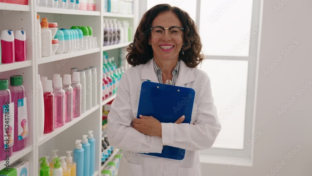 Middle age woman pharmacist smiling confident holding clipboard at pharmacy Middle age woman pharmacist smiling confident holding clipboard at pharmacy