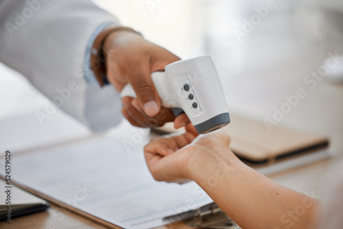 Medical doctor measure with infrared digital thermometer in a clinic consulting appointment for covid. Healthcare worker check for coronavirus for health and safety in hospital office
