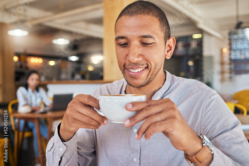 Man enjoying a cup of coffee, while smiling and sitting at a cafe relaxing. Businessman drinking tea or caffeine at restaurant. Relaxed and happy male holding a mug or beverage in a coffee shop