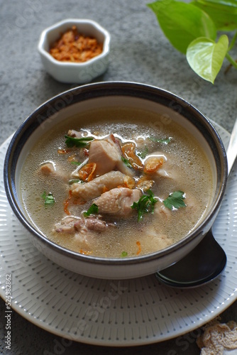 a bowl of chicken soup in grey background