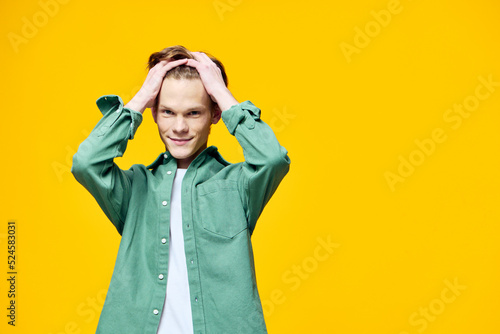guy in fashionable clothes posing on a yellow background holding his head