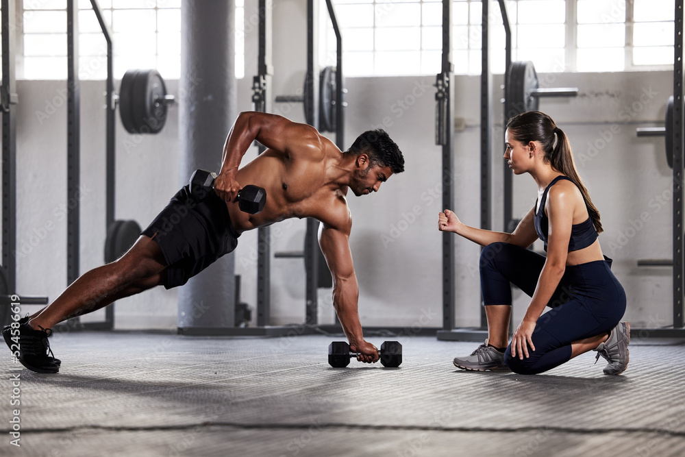 Muscular, sports man with female gym instructor or fitness coach doing body  building workout, push up plank exercise. Active male athlete weightlifting  in wellness center with trainer for motivation. Stock Photo