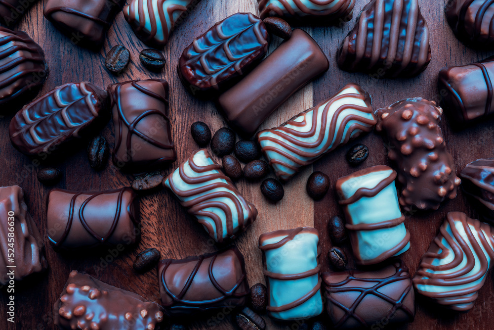 close up of colorful chocolates  and coffee roasted beans on wooden background