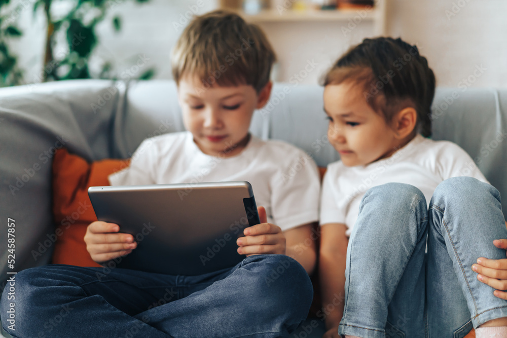 Children sitting on the couch watching videos on the tablet. Children sitting on the couch watching videos on the tablet.