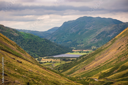 Beautiful view of mountains and distant lake in English Lake District at the end of summer with grazing sheep 