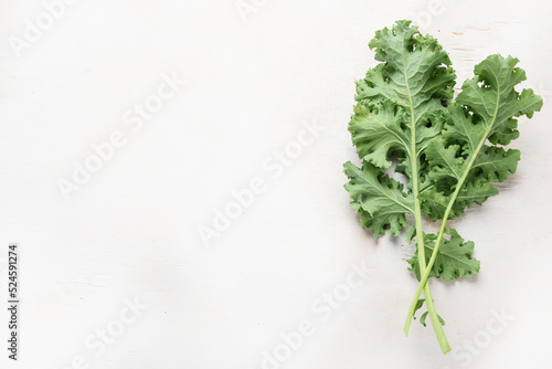 Fresh green curly kale leaves on neutral background.
