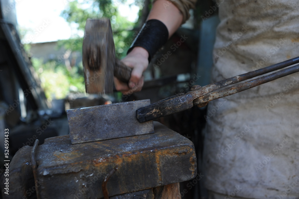 Almaty, Kazakhstan - 09.24.2015 : A blacksmith makes a metal holder for knives and tools in the workshop.