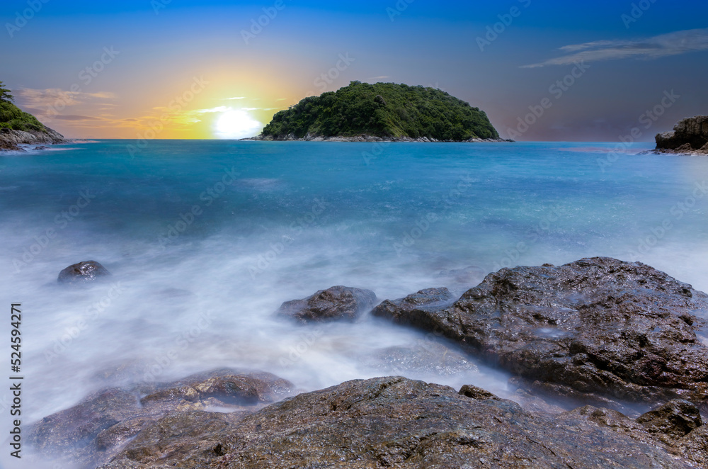 Naiharn Beach in Phuket Thailand, turquoise blue waters, lush green mountains colourful skies. Phuket is a tropical island many palms