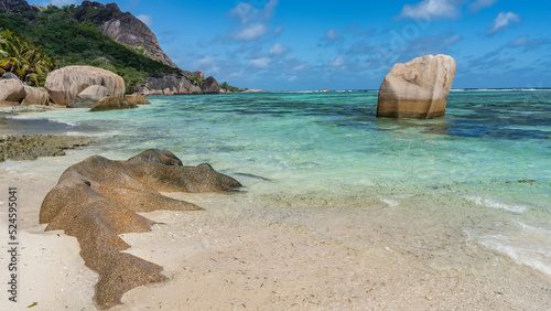Beautiful tropical beach. Picturesque boulders on the sand and in turquoise water. Lush vegetation on the hillside. Blue sky with clouds. Seychelles. La Digue. Anse Source D’Argent beach © Вера 
