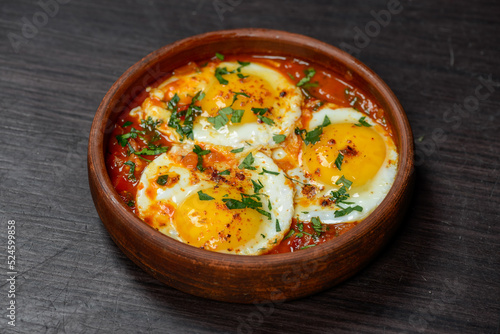 fried scrambled eggs in a clay pan on a dark background 