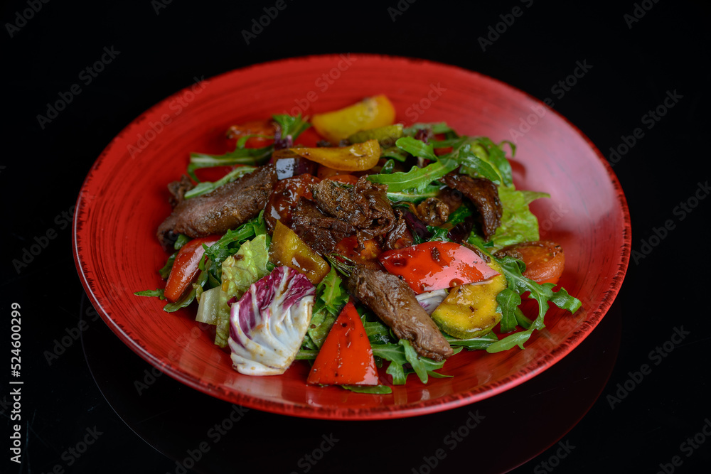 warm salad with veal in a red plate
